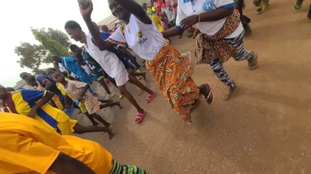 Togo: Femmes en pagnes et sandales, enfants pieds nus forcés de sortir pour courir dans les rues de Dapaong